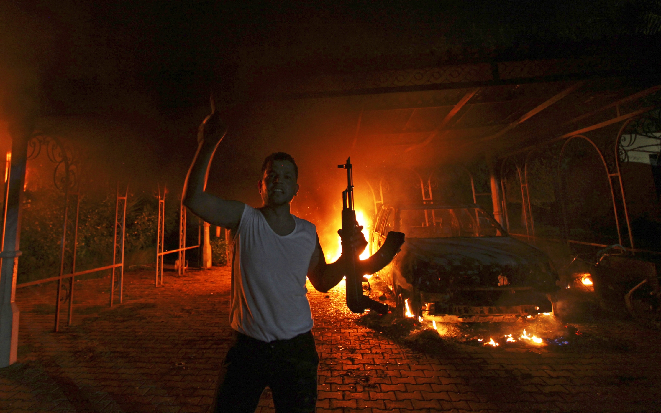 A protester reacts as the U.S. Consulate in Benghazi is seen in flames